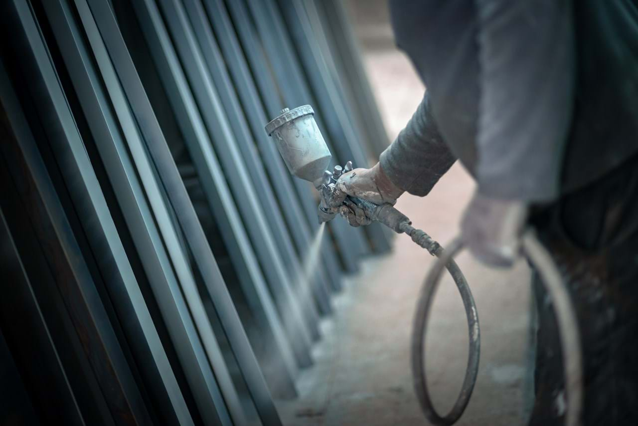 Man sprays with paint on a large metal object