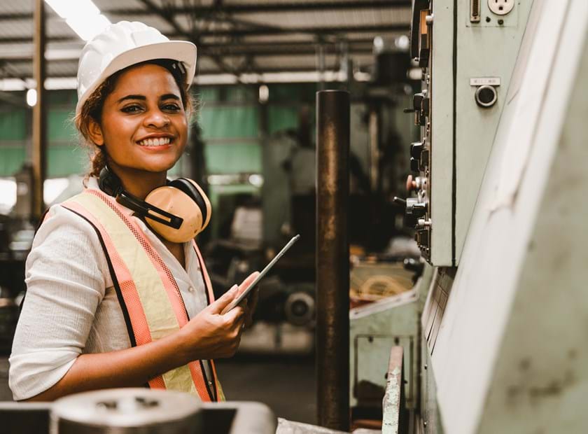 Kvinde smiler ved en industrimaskine