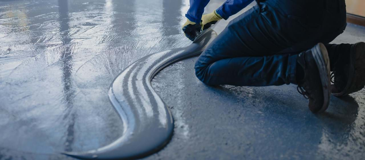 Mand påfører epoxy maling på betongulve